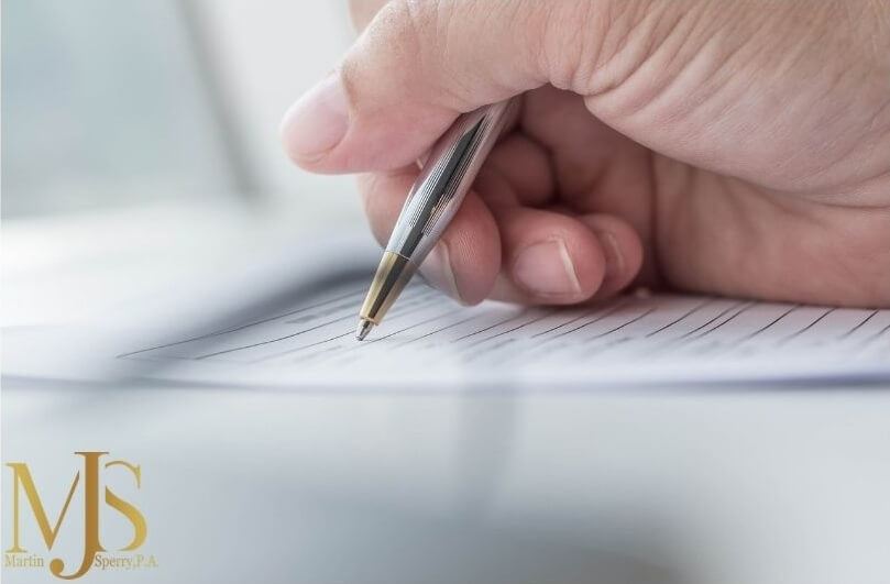 A person filing out Florida long-term disability paperwork with a pen